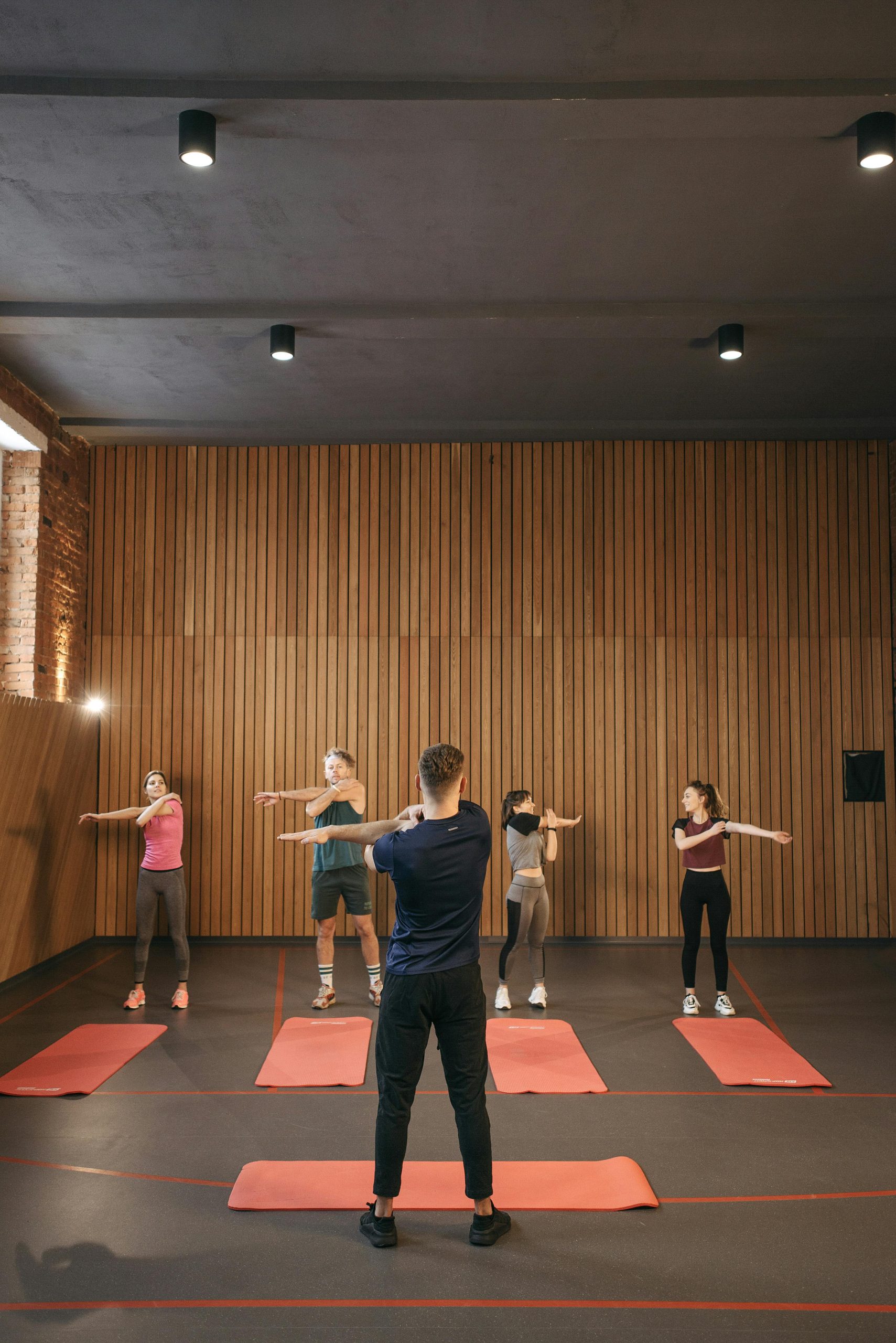 Mélanie A diverse group of adults stretching together in an indoor fitness class, led by an instructor.