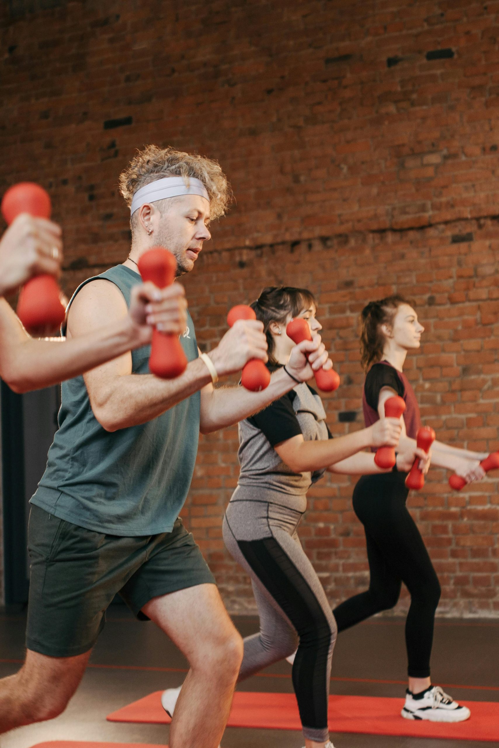 Diverse group exercising with dumbbells in an indoor gym setting, promoting healthy lifestyle.